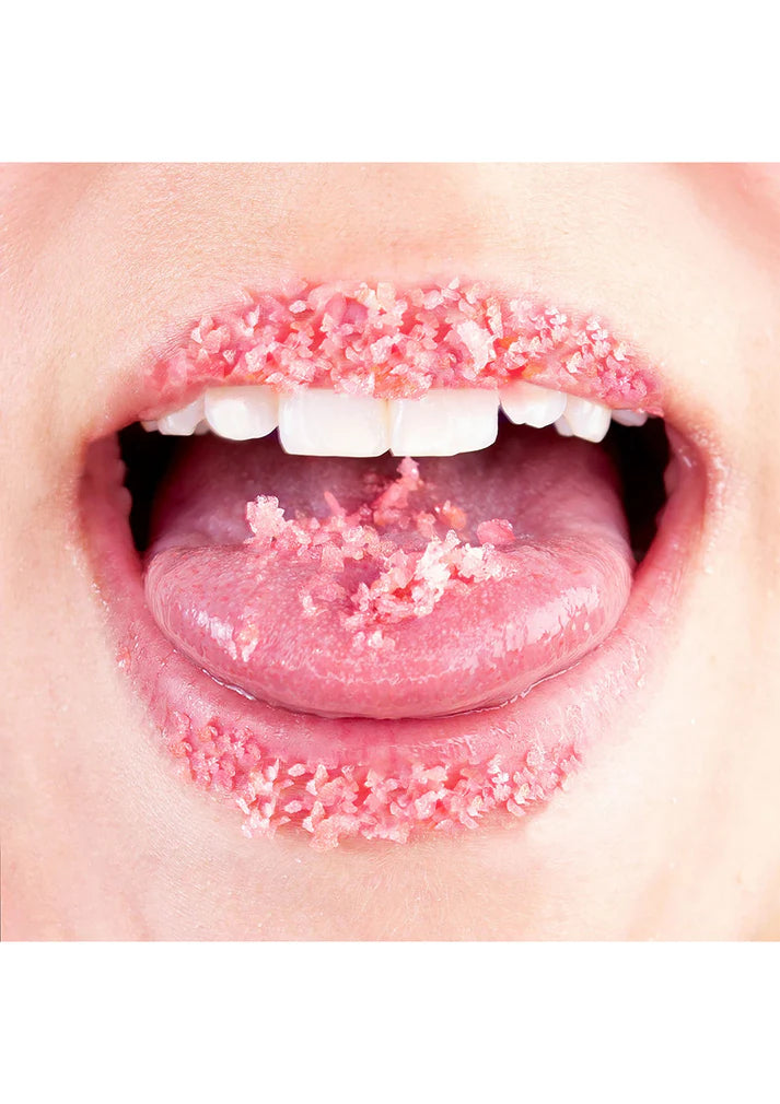 Close-up of a mouth with pink sugar crystals on the tongue and lips.